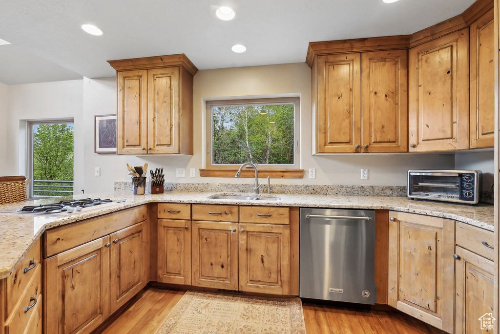 Kitchen with stainless steel dishwasher, a sink, gas stovetop, light wood-style flooring, and recessed lighting