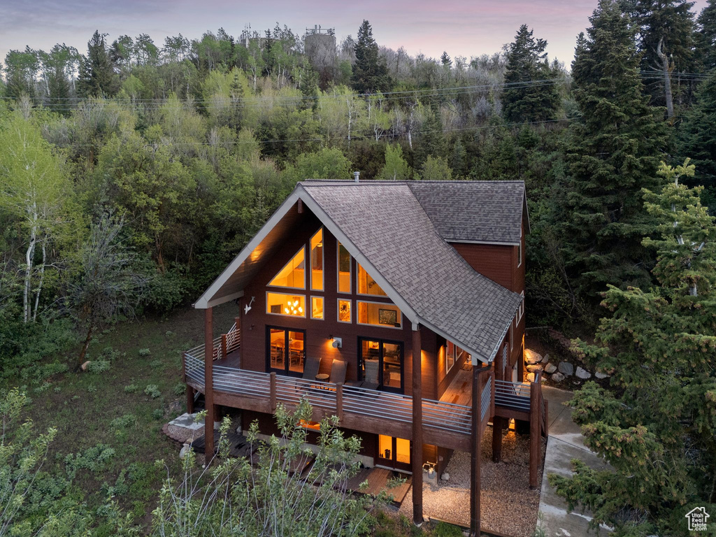 Back of house at dusk featuring a shingled roof
