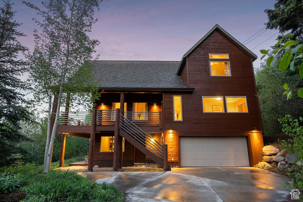 View of front of property with a garage, stairway, concrete driveway, and a shingled roof