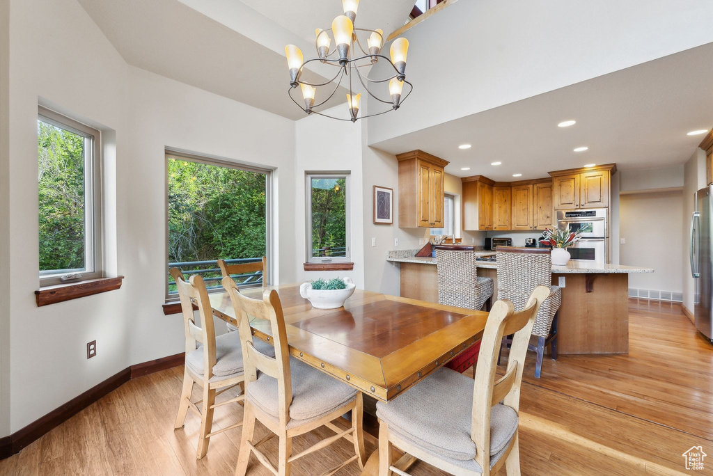Dining room with light wood-style floors, a chandelier, baseboards, and recessed lighting