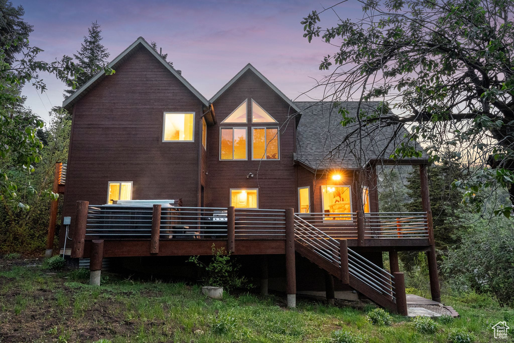 Back of house at dusk featuring a deck