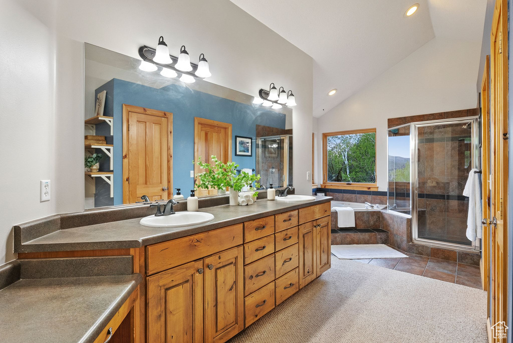 Bathroom featuring a stall shower, double vanity, vaulted ceiling, recessed lighting, and a bath