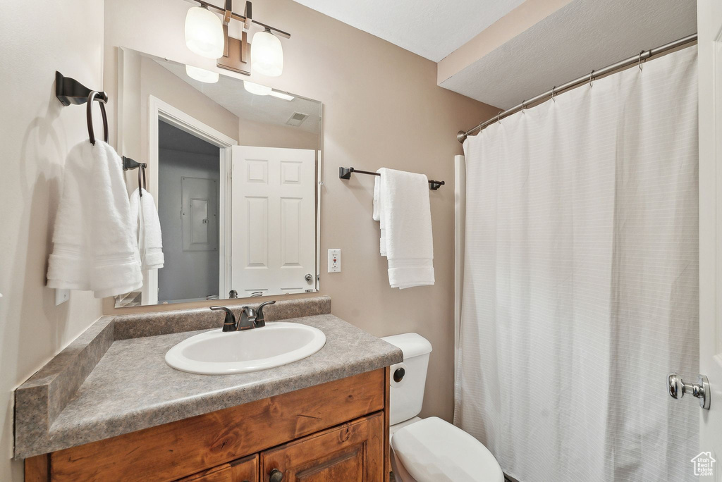 Bathroom with toilet, vanity, and curtained shower