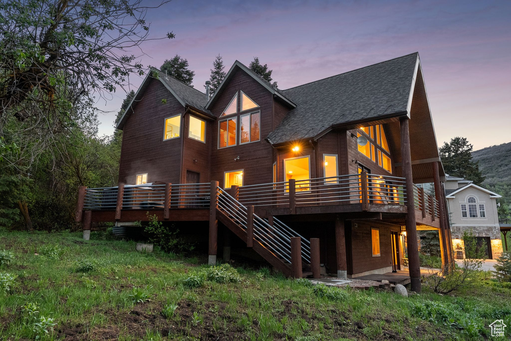 Back of property with roof with shingles, a wooden deck, and stairs