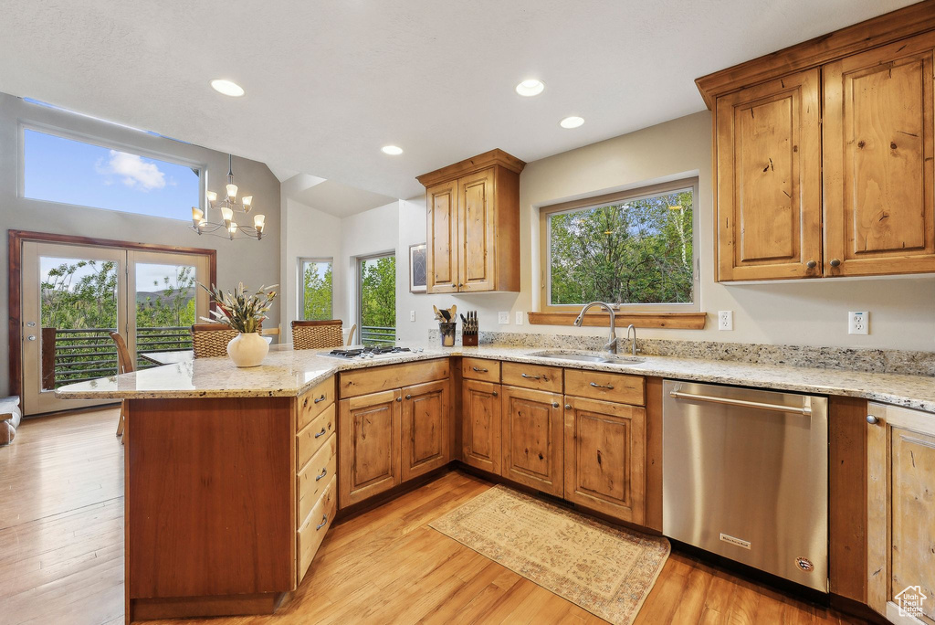 Kitchen featuring stainless steel dishwasher, a sink, a peninsula, light stone countertops, and vaulted ceiling