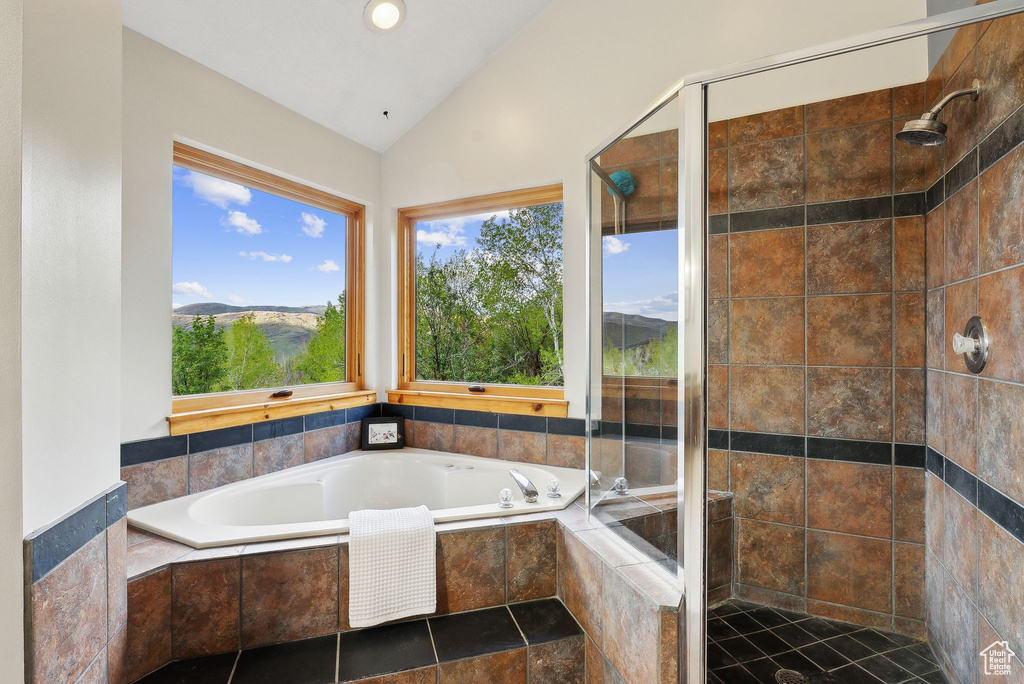 Bathroom featuring lofted ceiling, a garden tub, and a shower stall