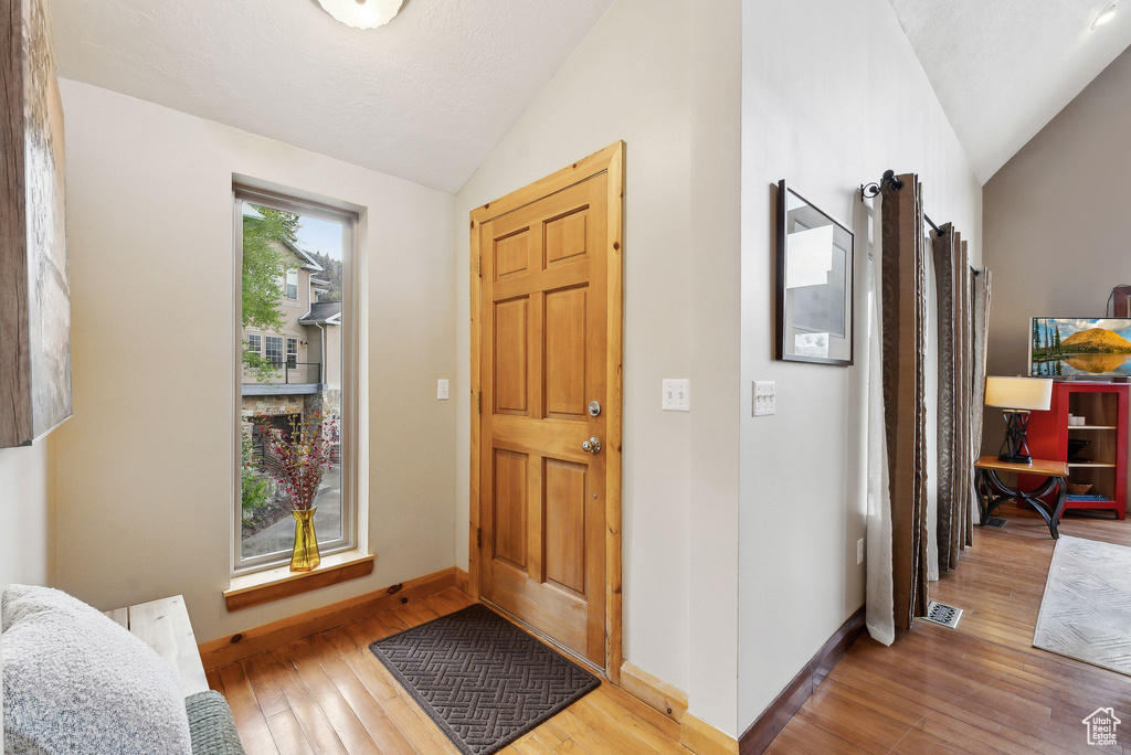 Foyer with vaulted ceiling, wood finished floors, and baseboards