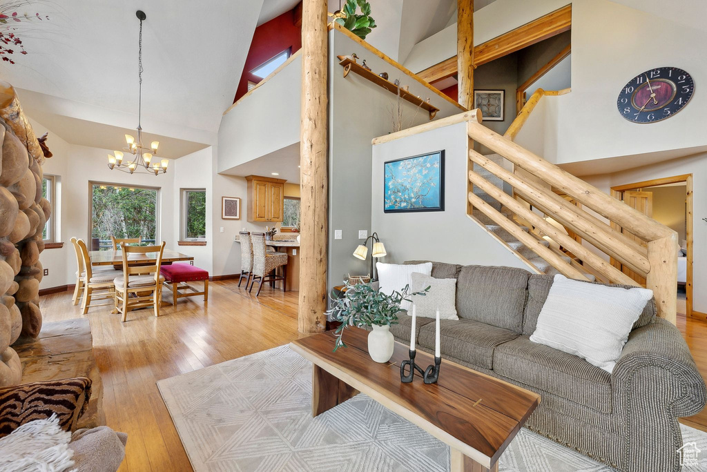 Living room featuring hardwood / wood-style floors, a chandelier, stairway, a high ceiling, and baseboards