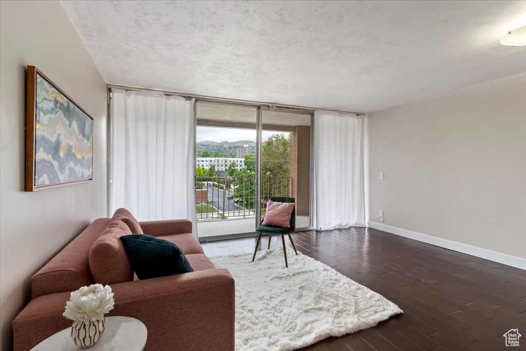 Living area with a textured ceiling, baseboards, dark wood-style flooring, and expansive windows