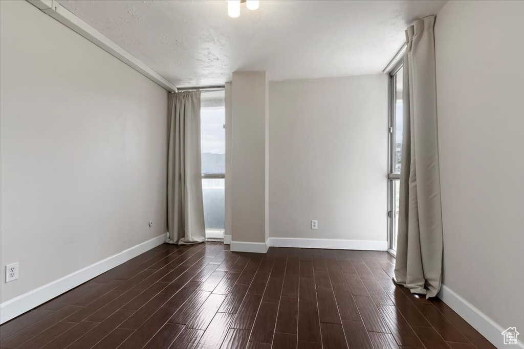 Empty room with baseboards and dark wood-style floors