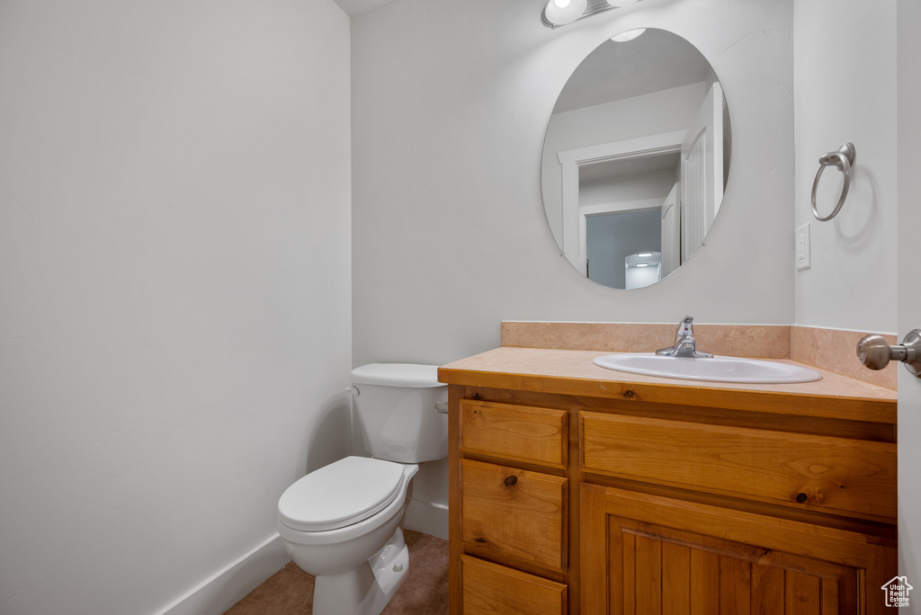 Bathroom with toilet, vanity, baseboards, and tile patterned floors
