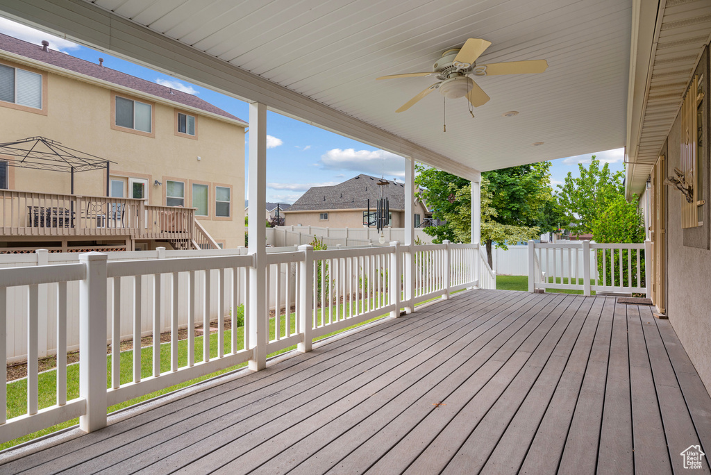 Wooden terrace featuring a fenced backyard, ceiling fan, and a residential view