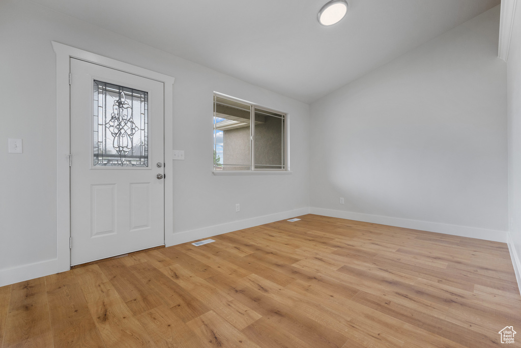 Entrance foyer with vaulted ceiling, light wood-type flooring, and baseboards