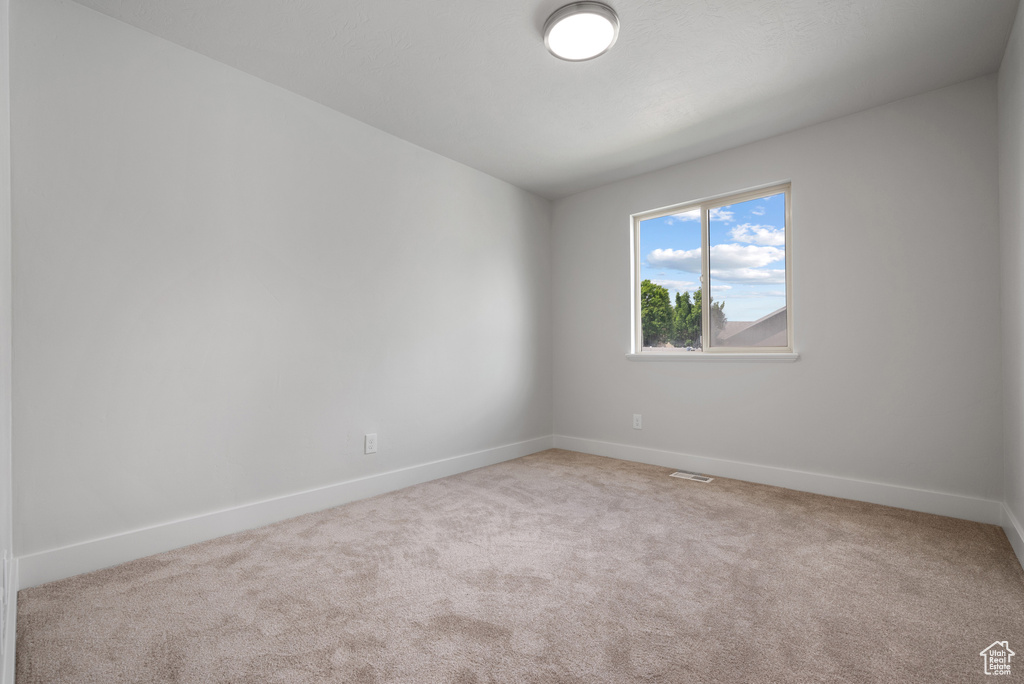 Carpeted spare room featuring baseboards