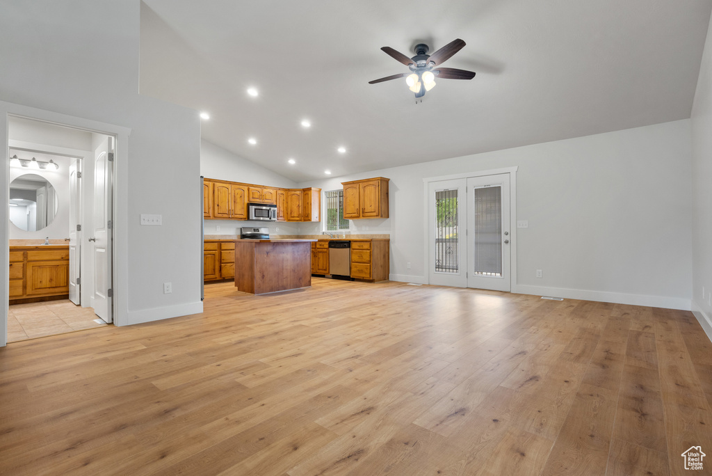 Kitchen featuring stainless steel appliances, a center island, open floor plan, light wood-style flooring, and a ceiling fan