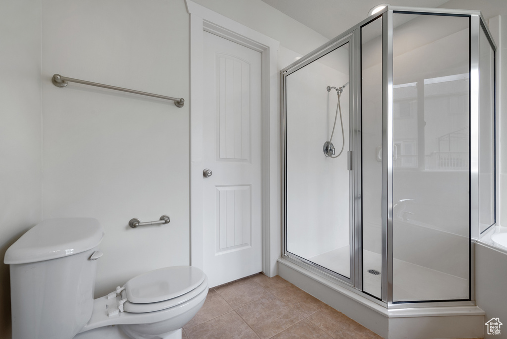 Full bath featuring toilet, a shower stall, and tile patterned floors