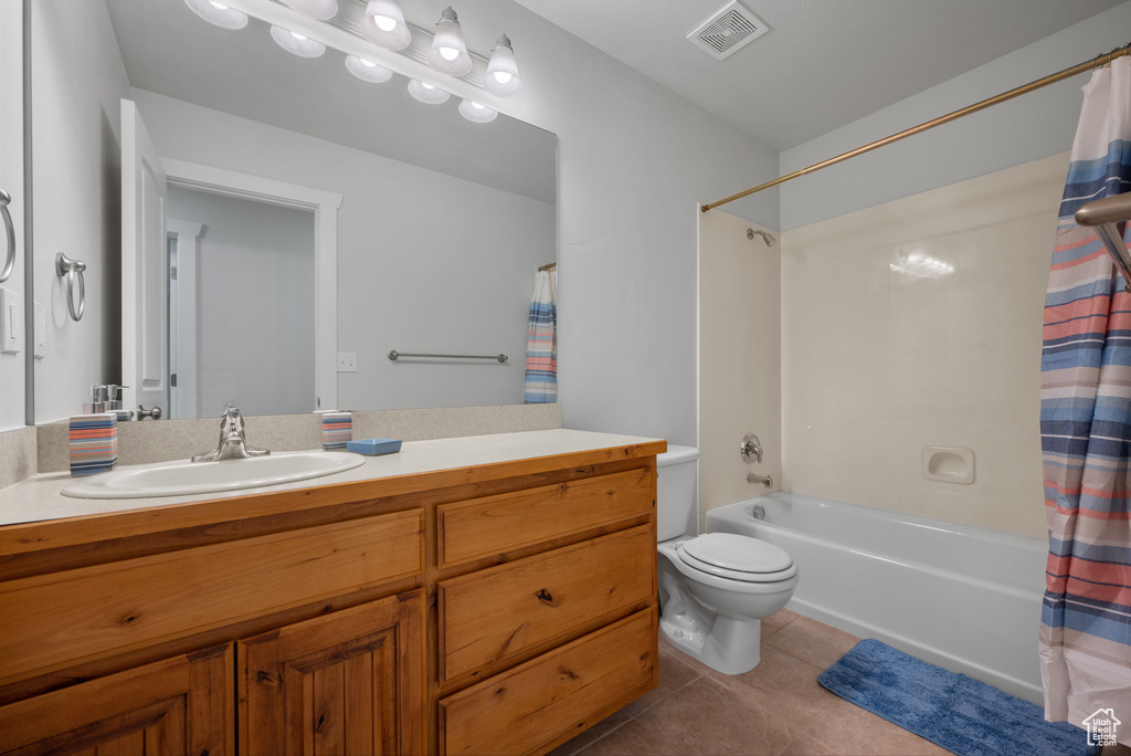 Bathroom featuring tile patterned floors, vanity, shower / bath combo with shower curtain, and toilet