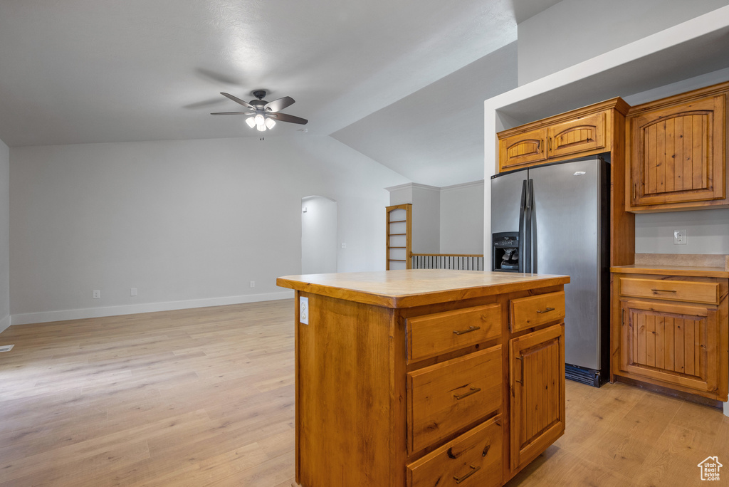 Kitchen featuring stainless steel fridge, ceiling fan, light wood-style flooring, a center island, and vaulted ceiling