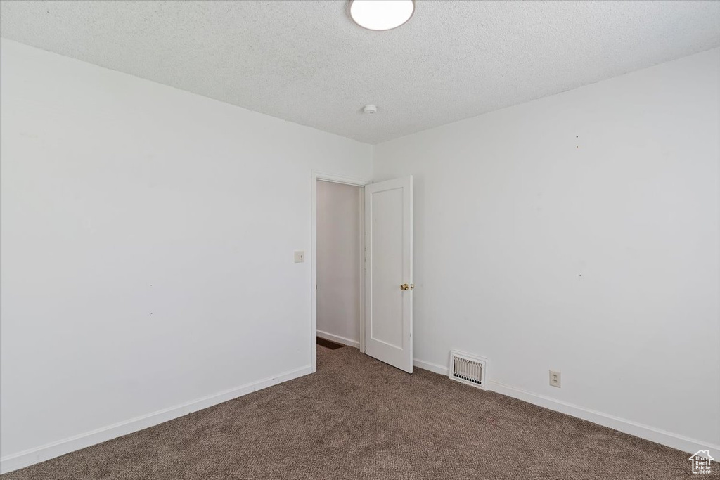 Carpeted spare room with baseboards and a textured ceiling