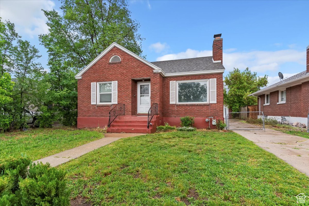 Bungalow featuring brick siding, a chimney, and roof with shingles