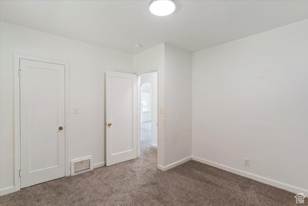 Unfurnished bedroom with carpet, baseboards, and arched walkways