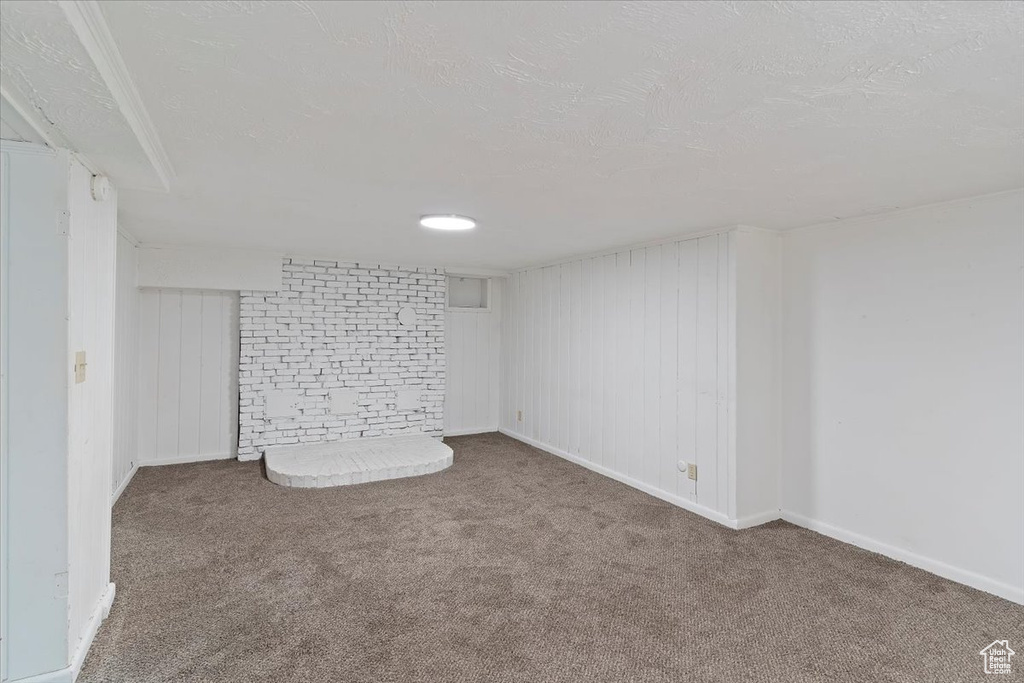 Finished below grade area featuring carpet floors, a textured ceiling, and baseboards
