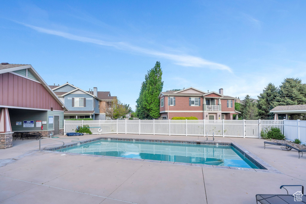 Community pool with a patio, fence, and a residential view