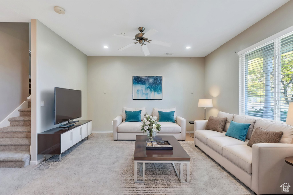Living area with a ceiling fan, baseboards, recessed lighting, light colored carpet, and stairway