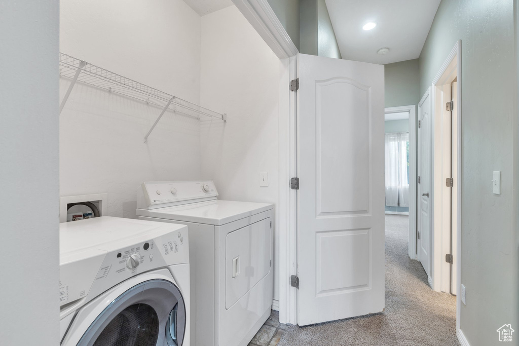 Laundry area with separate washer and dryer, light carpet, and baseboards