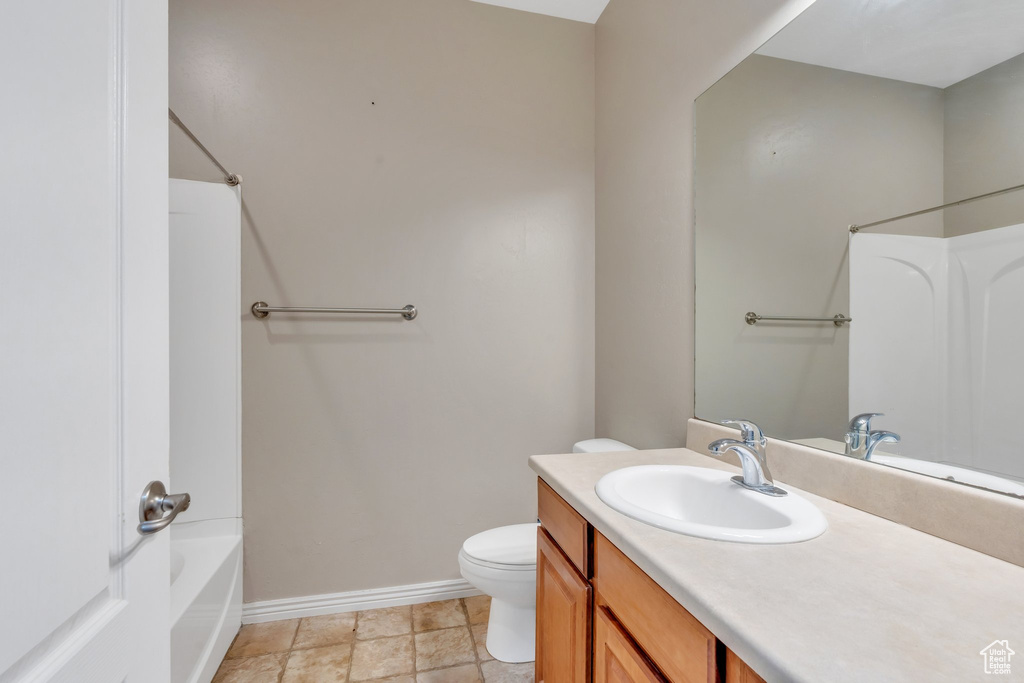 Bathroom featuring baseboards, toilet, vanity, and shower / tub combination