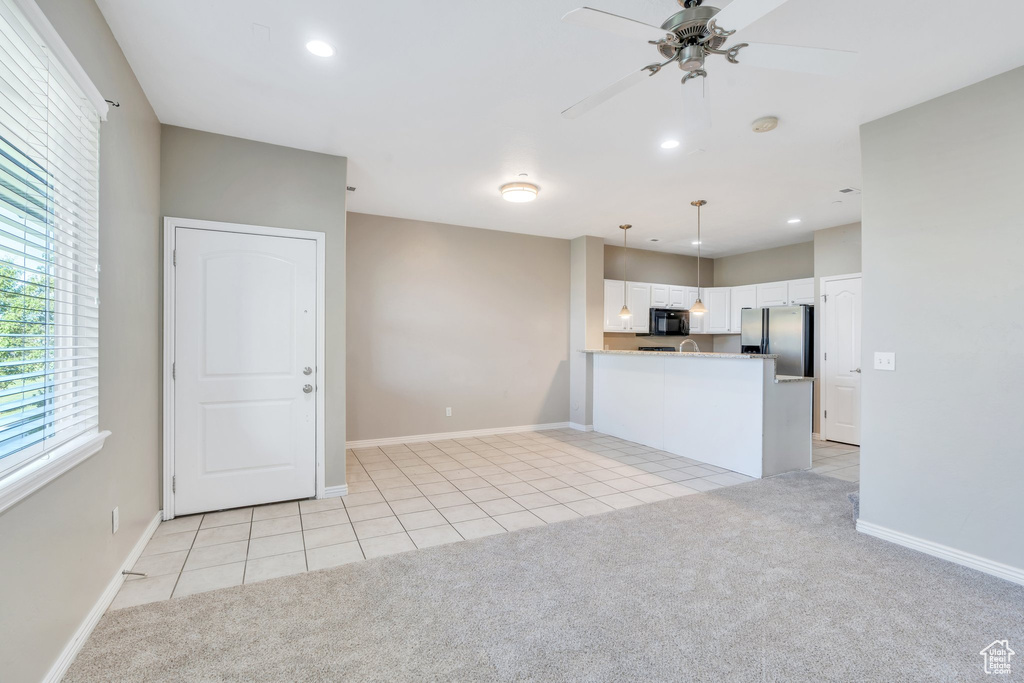 Unfurnished living room with light carpet, light tile patterned floors, ceiling fan, and recessed lighting