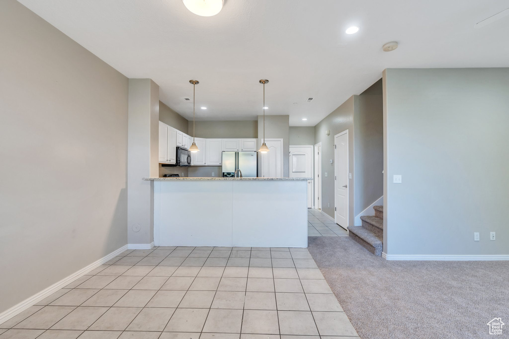 Kitchen featuring stainless steel fridge with ice dispenser, black microwave, white cabinets, recessed lighting, and a peninsula