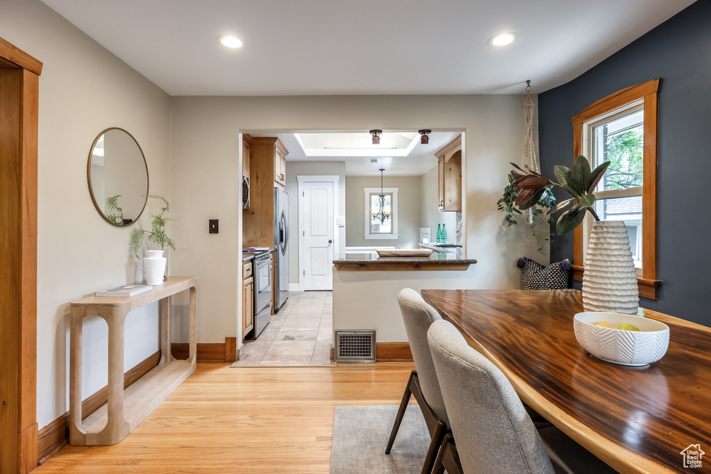 Dining room featuring light wood-style floors, recessed lighting, baseboards, and a tray ceiling