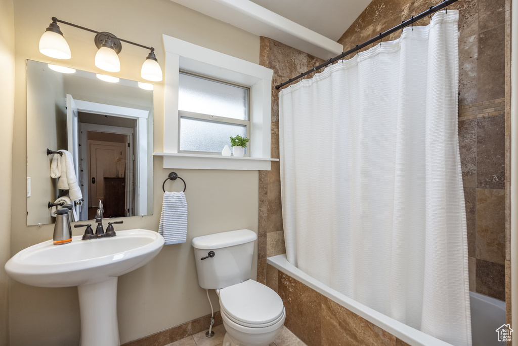 Full bathroom with tiled shower / bath combo, toilet, and a sink