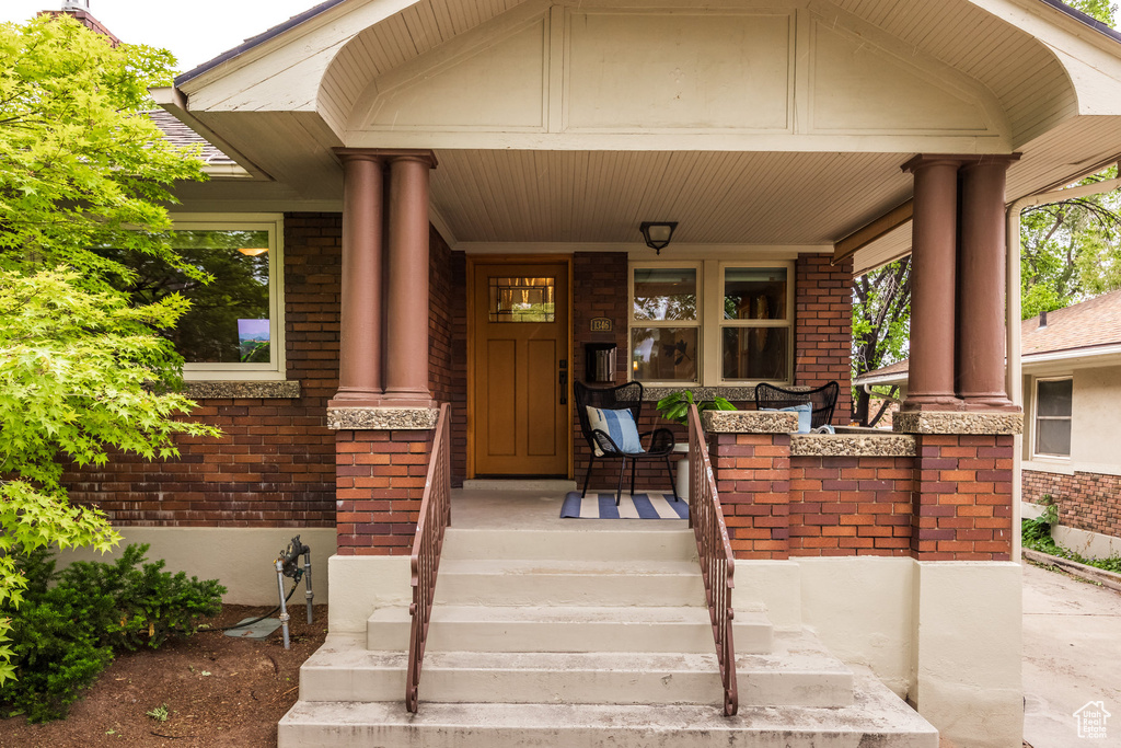 View of exterior entry with brick siding and covered porch