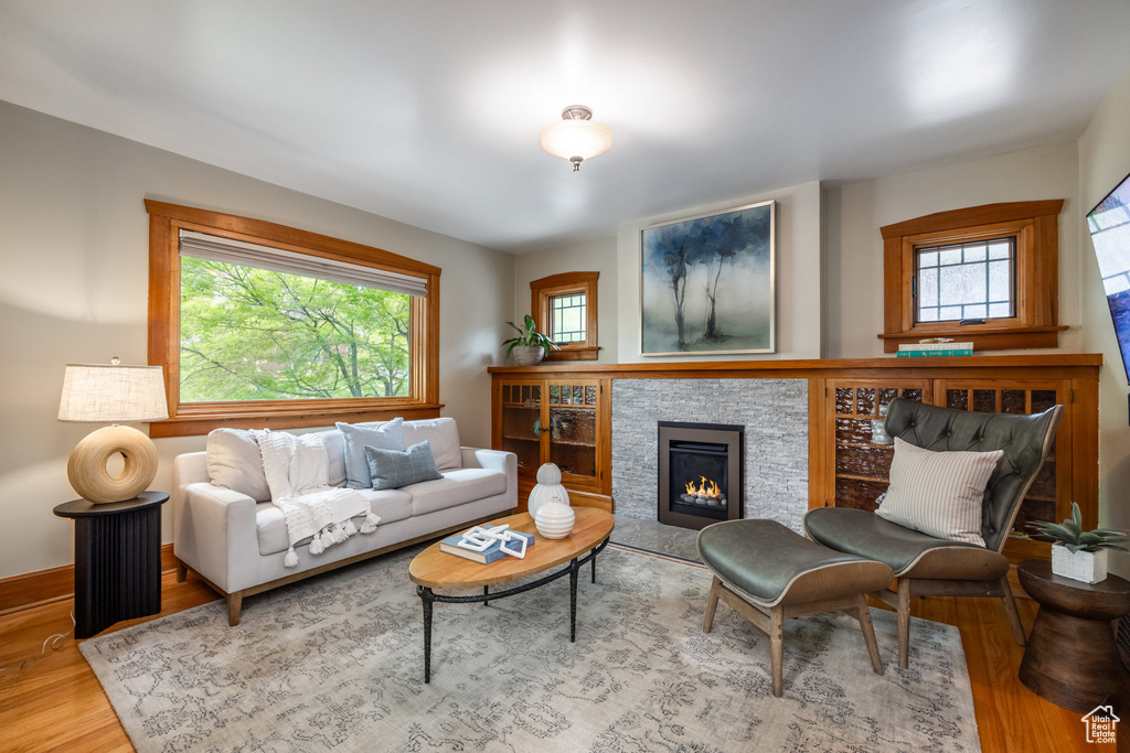 Living area with wood finished floors, plenty of natural light, a lit fireplace, and baseboards
