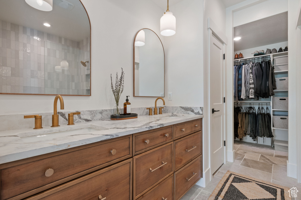 Bathroom with double vanity, a walk in shower, and a spacious closet