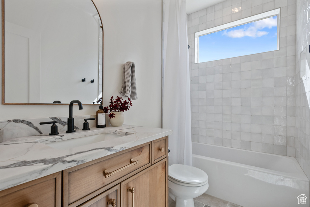 Bathroom featuring toilet, vanity, and shower / bath combination with curtain