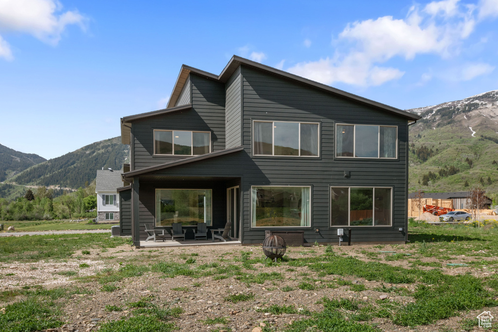 Rear view of house with a mountain view, a fire pit, and a patio