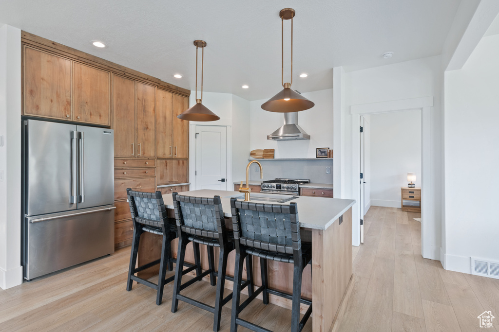 Kitchen featuring high quality appliances, light wood-type flooring, light countertops, hanging light fixtures, and recessed lighting