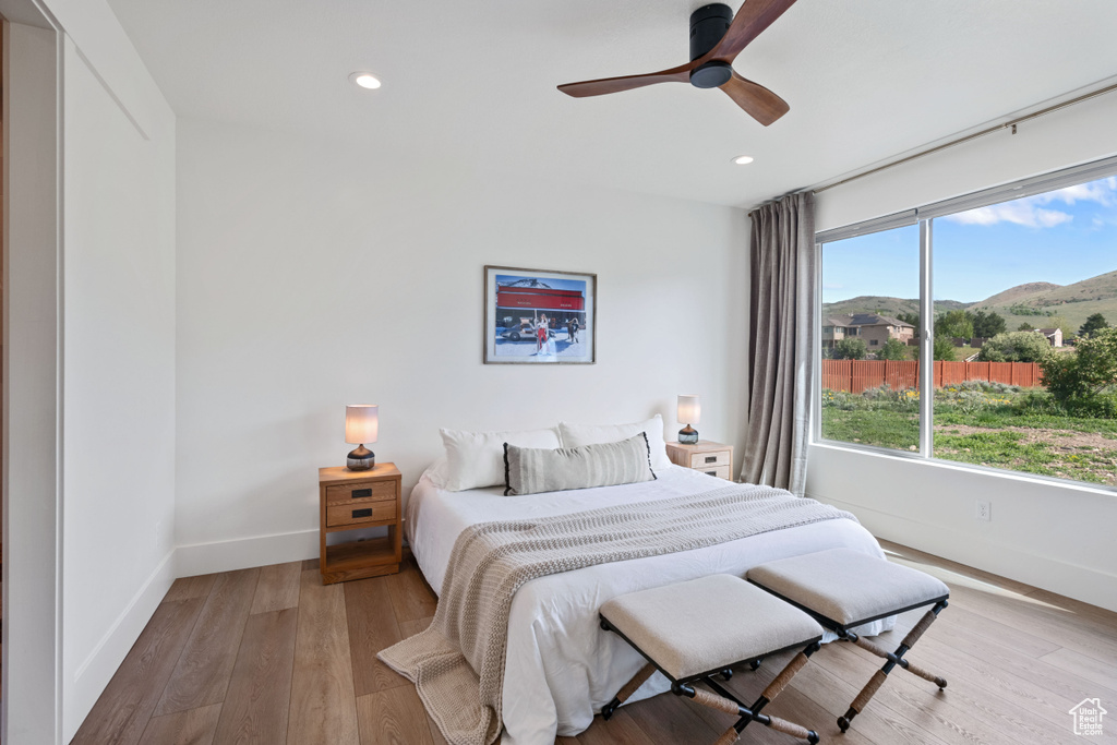 Bedroom with baseboards, light wood-style floors, recessed lighting, a mountain view, and ceiling fan