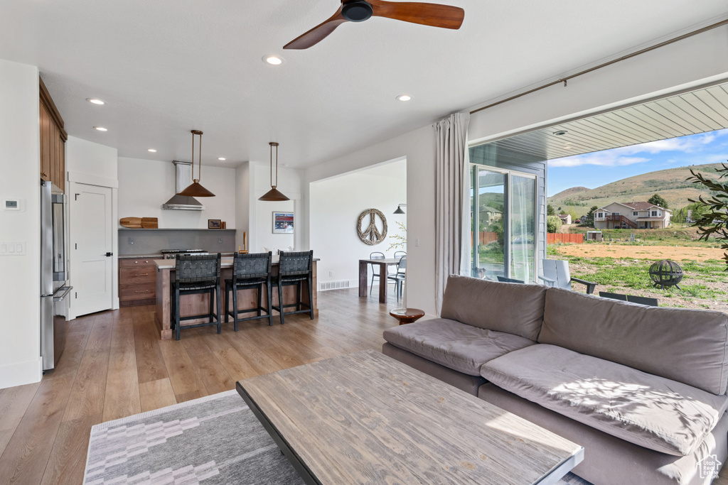 Living room with a ceiling fan, recessed lighting, a mountain view, and light wood-style floors