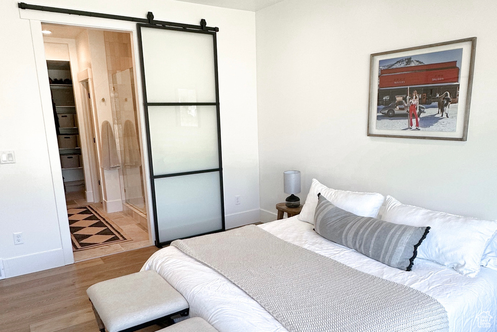 Bedroom with wood finished floors, baseboards, and a barn door