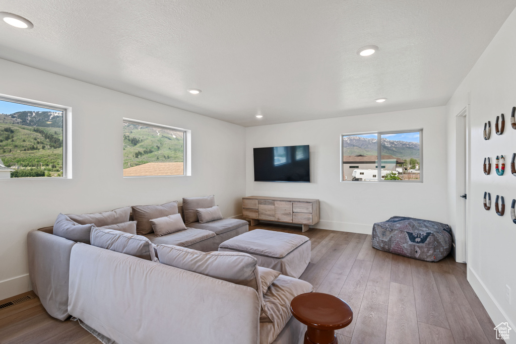Living room with healthy amount of natural light, hardwood / wood-style floors, and recessed lighting