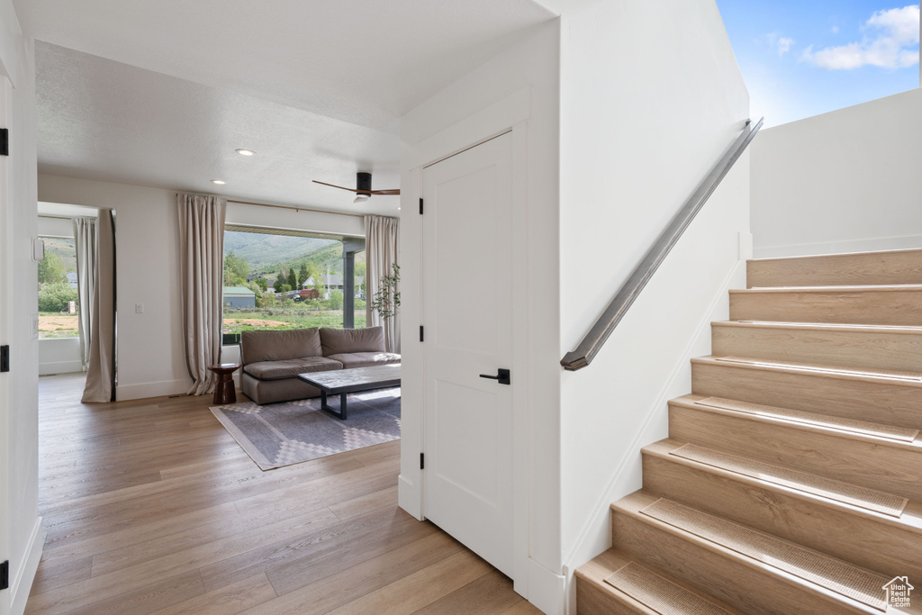 Stairs with wood finished floors, plenty of natural light, baseboards, and recessed lighting