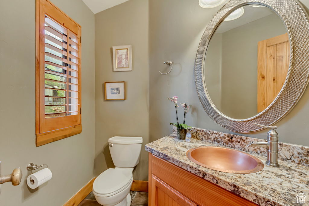 Half bath with toilet, vanity, and baseboards