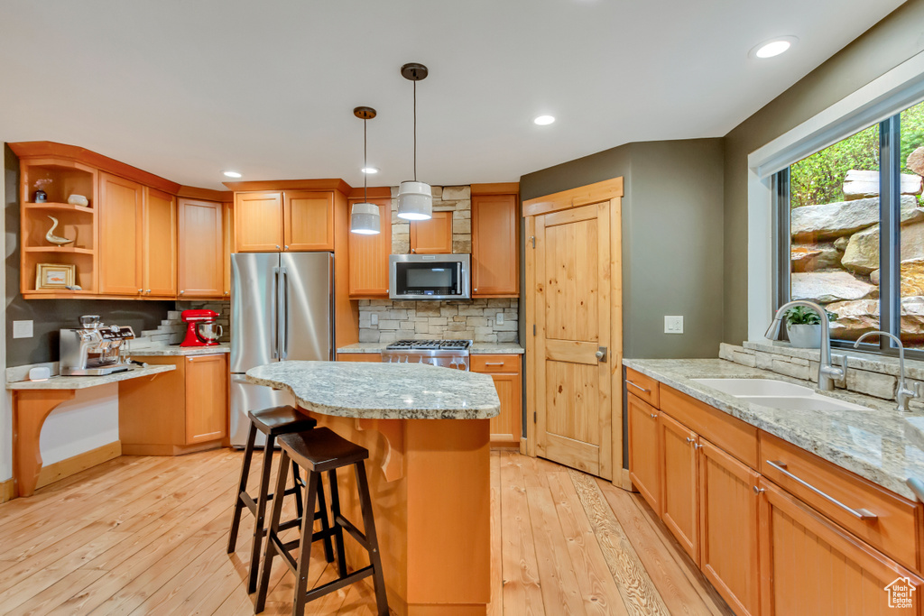Kitchen with appliances with stainless steel finishes, a sink, light wood finished floors, backsplash, and recessed lighting