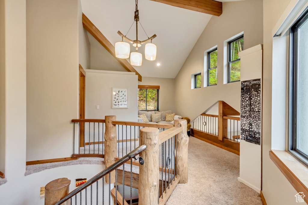 Hallway with high vaulted ceiling, beamed ceiling, plenty of natural light, and an upstairs landing