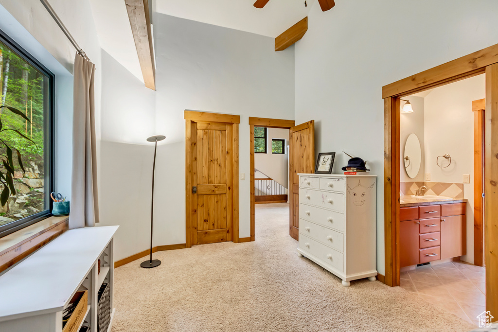 Living area featuring a ceiling fan, light colored carpet, and high vaulted ceiling