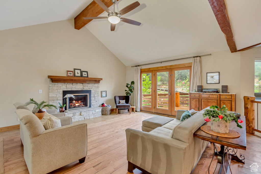 Living area with beamed ceiling, light wood-style flooring, a ceiling fan, a fireplace, and high vaulted ceiling